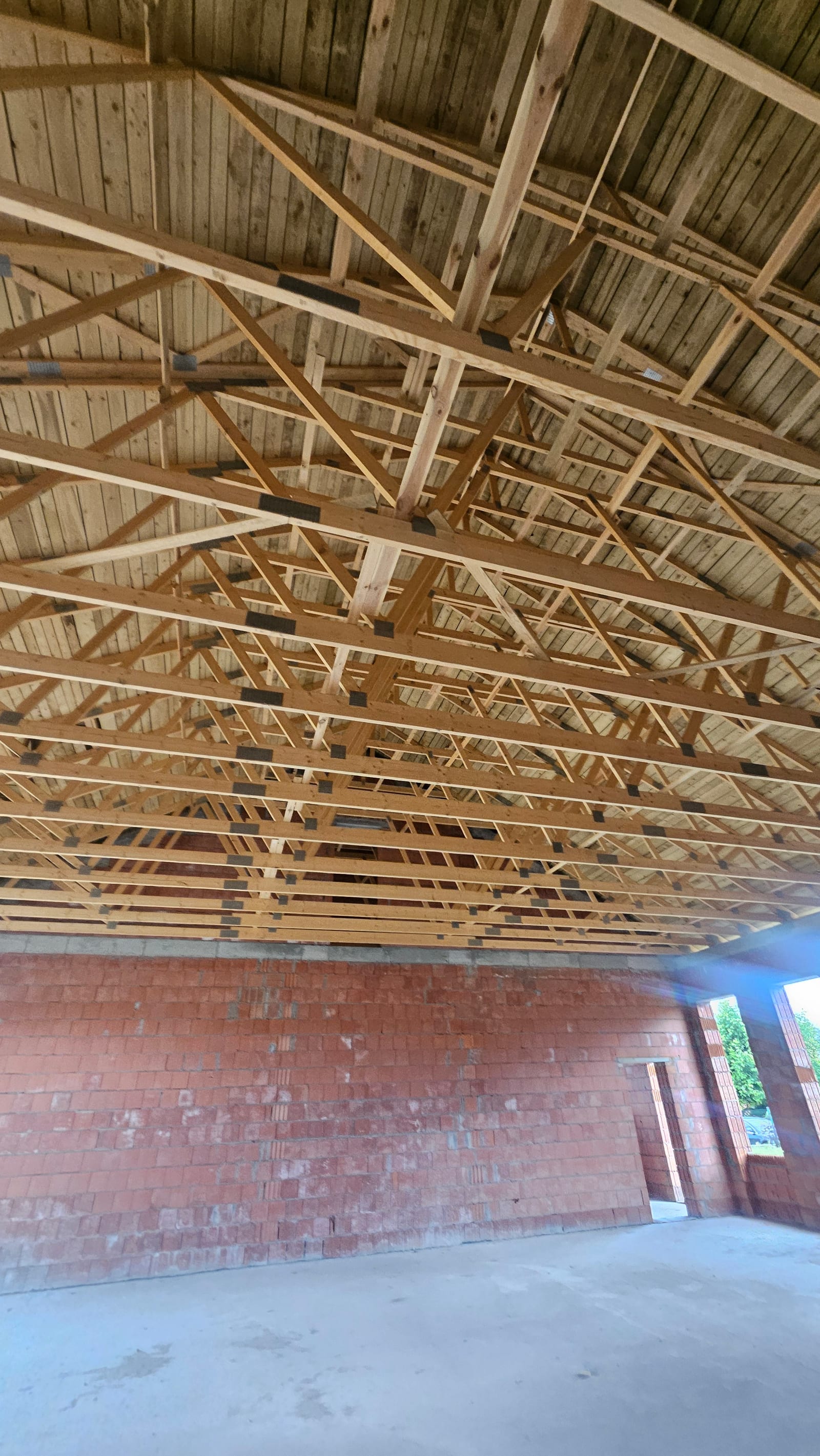 Drewniane wiązary dachowe widziane od wewnątrz, nad ścianami z pustaków ceramicznych